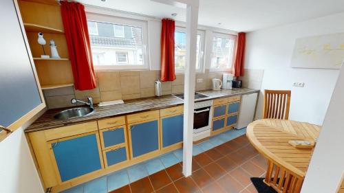 Una pequeña cocina con un fregadero y una mesa. en Haus Wiesenweg14 M, en Laboe