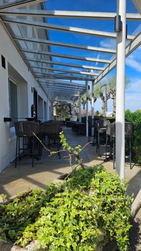 a covered patio with tables and chairs and plants at Auberge de la Marine in Losne