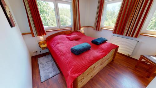 1 dormitorio con 1 cama roja y 2 almohadas en Mühle W02 en Lutterbek