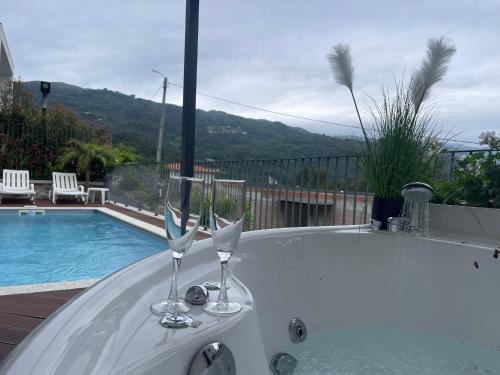 a bath tub with two wine glasses sitting next to a swimming pool at Lamegos Guesthouse II - Gerês in Terras de Bouro