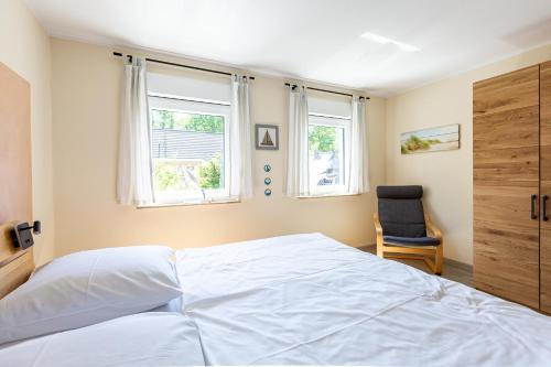 a bedroom with a bed and a chair and two windows at Ostseeromantik in Neuhaus