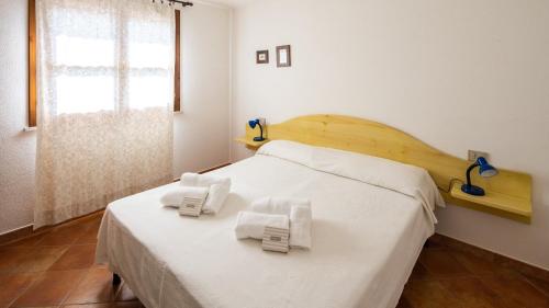 Un dormitorio con una cama blanca con toallas. en Villa Cala Liberotto, en Cala Liberotto