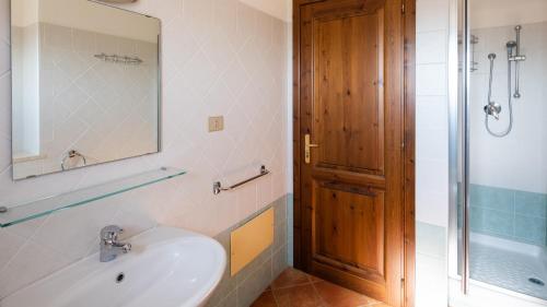 een badkamer met een wastafel, een spiegel en een douche bij Villa Cala Liberotto in Cala Liberotto