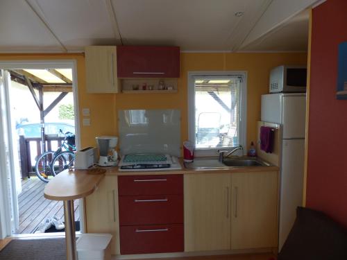 une petite cuisine avec un évier et un réfrigérateur dans l'établissement Le Repos du Baigneur - Mobile Home à Soulac sur Mer, à Soulac-sur-Mer