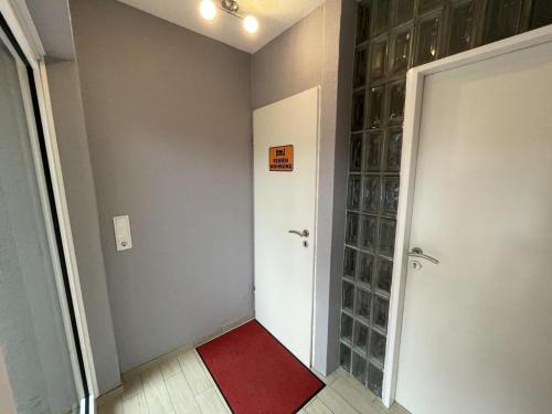 a bathroom with a red rug next to a door at Fewo Kuhnert in Laboe