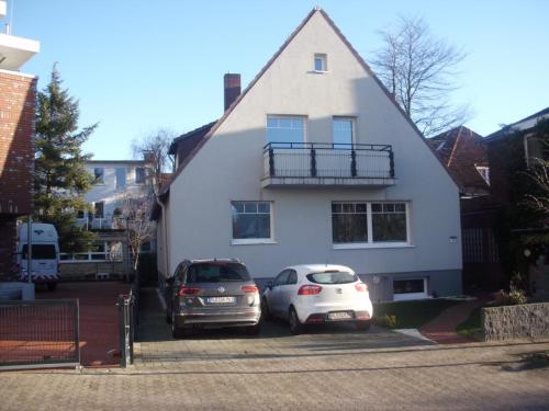 two cars parked in front of a white house at Fewo Kuhnert in Laboe