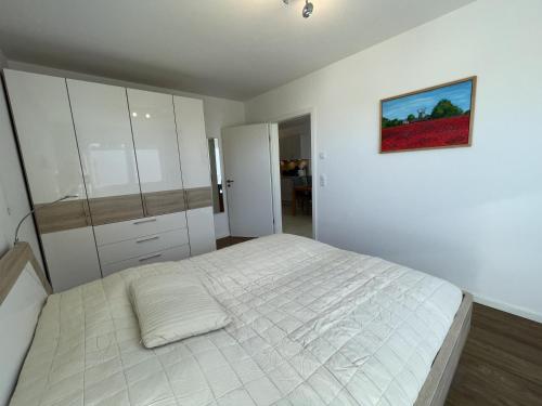 ein Schlafzimmer mit einem weißen Bett und einem Gemälde an der Wand in der Unterkunft Ferienwohnung Fördekönig in Laboe