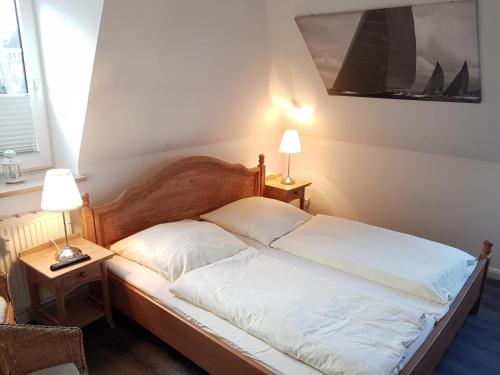1 dormitorio con 1 cama con sábanas blancas y 2 lámparas en Wiesenweg W17 en Laboe