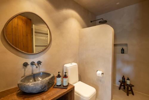 a bathroom with a sink and a toilet and a mirror at Casa Oliva Guesthouse in Tris Elies