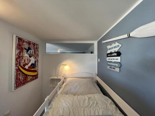 a small bedroom with a bed and signs on the wall at Meerblickbude in Wendtorf