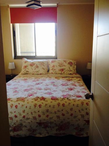 Un dormitorio con una cama con una manta de flores y una ventana en Casa de Daniela, en Valparaíso