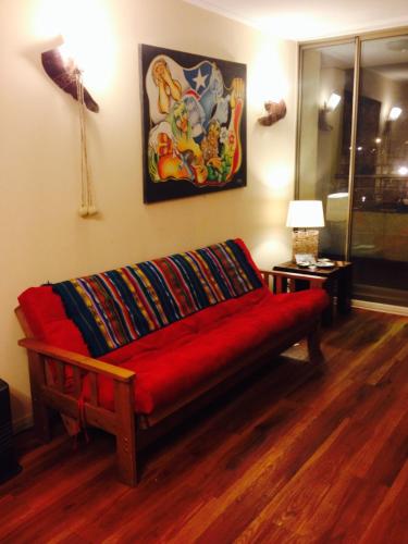 un sofá rojo en una habitación con una pintura en la pared en Casa de Daniela, en Valparaíso