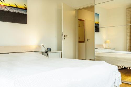 a bedroom with a white bed and a mirror at Villa Fördestrand W06 in Laboe