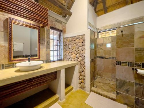 a bathroom with a sink and a shower with a mirror at Kanaan, Mabalingwe in Mabula