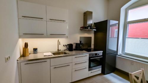 a kitchen with white cabinets and a sink and a window at Fewo Sanddüne nur wenige Minuten vom Hafen und Strand entfernt in Laboe