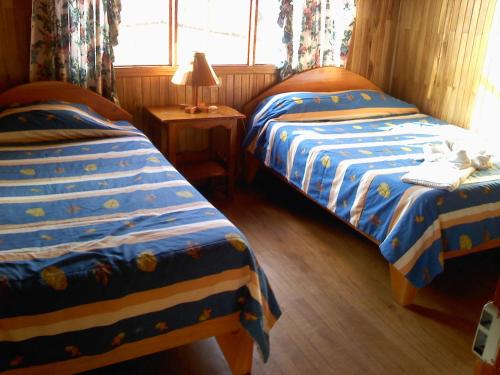 a bedroom with two beds and a lamp and a window at Hotel El Atardecer in Monteverde Costa Rica
