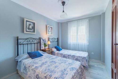 2 camas en un dormitorio con paredes azules en Ático en Novo Sancti Petri en Chiclana de la Frontera