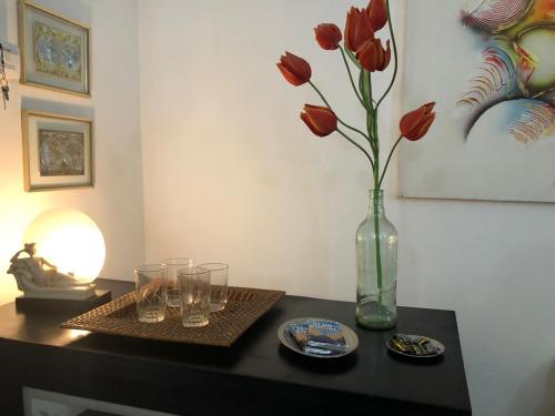 une table avec un vase avec des fleurs rouges et des verres dans l'établissement Chalé do Vale à 10 min de carro de Itacoatiara, à Niterói