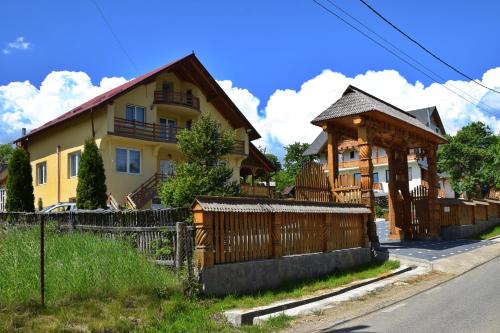 a house with a wooden fence in front of it at Pensiunea Maramu in Breb