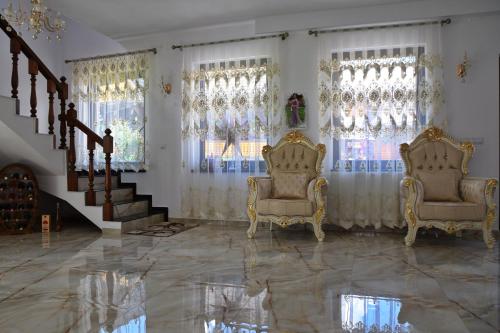 a living room with two chairs and a staircase at Pensiunea Maramu in Breb