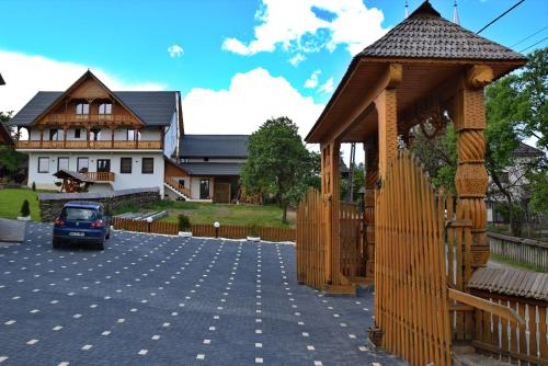 a house with a car parked in a parking lot at Pensiunea Maramu in Breb