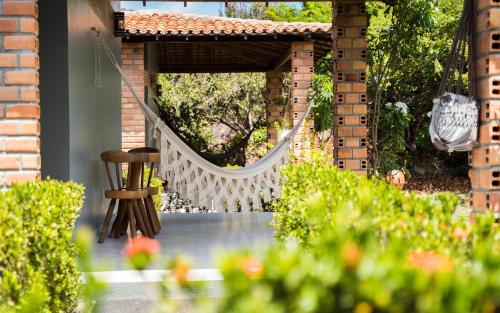 a white hammock in a garden with a chair at Hotel Pousada Rancho das Dunas in Santo Amaro