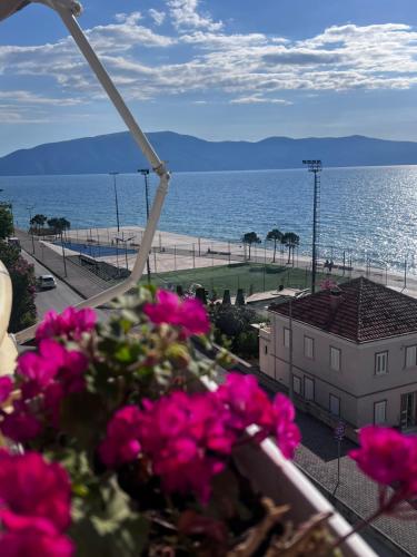 a view of the beach from a balcony with pink flowers at Hotel Lungomare in Vlorë