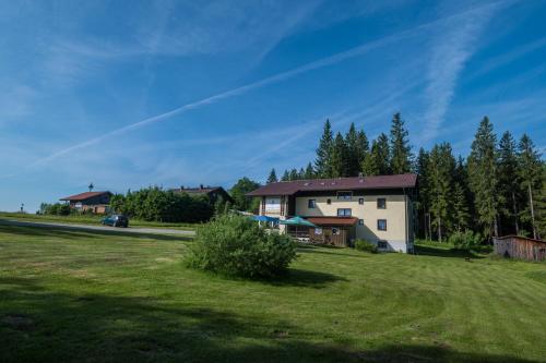 a house on a grassy field with trees in the background at Pension Arberwald in Bayerisch Eisenstein