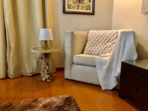 uma sala de estar com uma cadeira e uma mesa com um candeeiro em Chalé do Vale à 10 min de carro de Itacoatiara em Niterói
