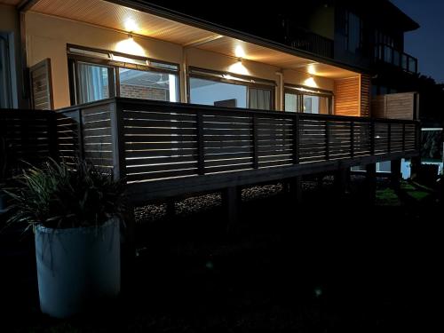 a house with a wooden deck with lights on it at Mitford The N I C E Condo in Morganʼs Bay