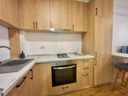 een keuken met houten kasten, een wastafel en een fornuis bij Studio No 5 Lebada Lake Residence in Pantelimon