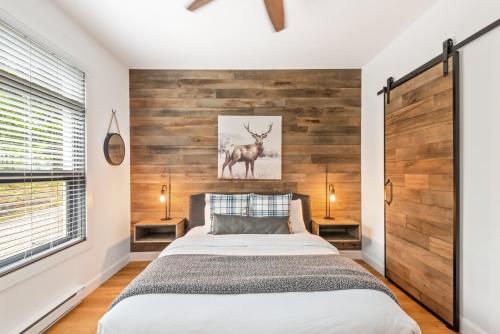 a bedroom with a bed and a wooden wall at Tremblant Prestige - Les Eaux 235-1 in Mont-Tremblant