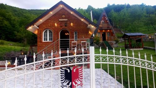 uma casa com uma cerca branca em frente em Vilat Pllumaj em Gropat e Selcës