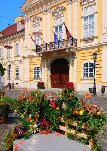 a yellow building with flowers in front of it at Fehérvár Cappuccino apartman City center, AC, Easy Parking in Székesfehérvár