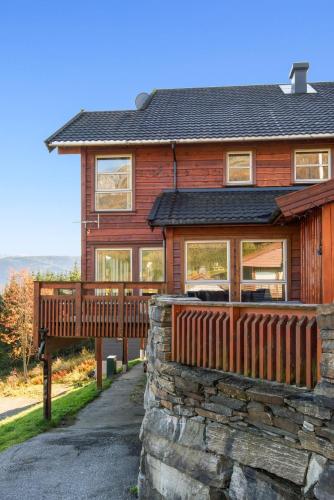 a house with a wooden fence and a stone wall at Voss Resort self-service apartments in Skulestadmo