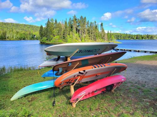 a pile of surfboards sitting on the grass near a lake at L'eau douce - Lumière naturelle en bord de lac in Saint-Donat-de-Montcalm