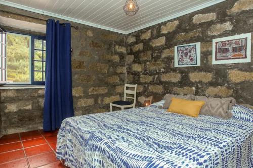 a bedroom with a bed and a stone wall at Casa da Avó Madalena in Fayal da Terra
