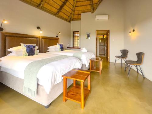 two beds in a room with two chairs at Kanaan, Mabalingwe in Mabula
