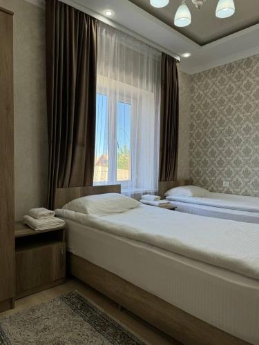 1 dormitorio con 2 camas y ventana en Айкол en Bokonbayevo
