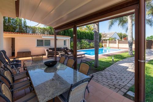 une terrasse avec une table, des chaises et une piscine dans l'établissement Casa junto al mar con jardín, à Sagonte