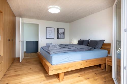a bedroom with a large bed with blue sheets at Villa with pool, garden & direct at lake in Spiez