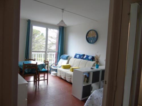 un salon avec un canapé blanc et une horloge au mur dans l'établissement idéal curiste, à Gréoux-les-Bains