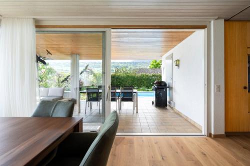 a living room with a table and chairs and sliding glass doors at Villa with pool, garden & direct at lake in Spiez