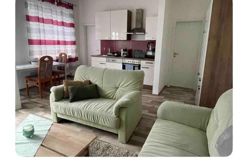 a living room with a green couch and a kitchen at TopTravel-LKW Parkplatz in Bad Hersfeld