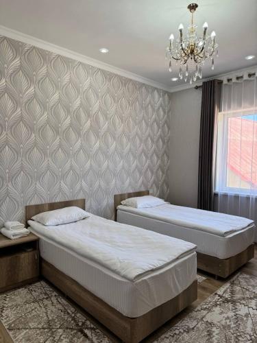 1 dormitorio con 2 camas y lámpara de araña en Айкол, en Bokonbayevo