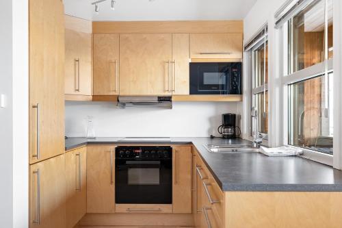 a kitchen with wooden cabinets and a black appliance at Voss Resort self-service apartments in Skulestadmo