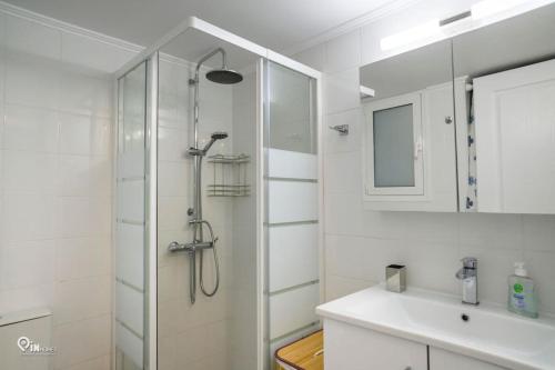 a white bathroom with a shower and a sink at Blue Ocean Luxury House in Nea Makri