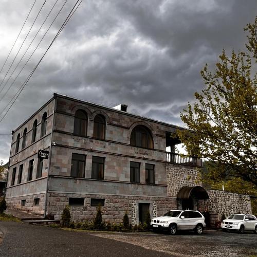 a stone building with two cars parked in front of it at Popock Goris in Goris