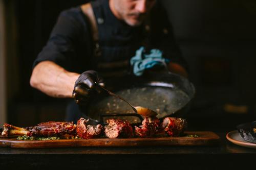 a man is preparing food on a plate with meat at La Morada Lodge - Valle de Uco in Vista Flores