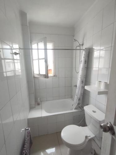 a white bathroom with a toilet and a bath tub at Hostal Vitalia in Santiago